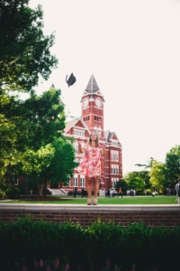 girl throwing graduation cap in front of Samford Hall at Auburn University